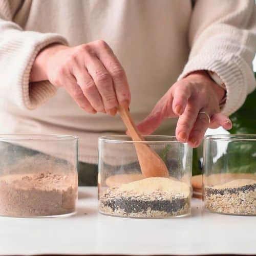 Stirring the dry protein overnight oats ingredients in small jars.