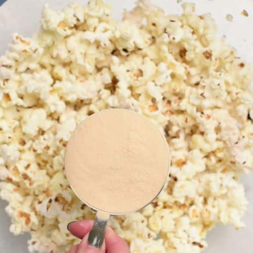 Adding protein powder to the popped corn.