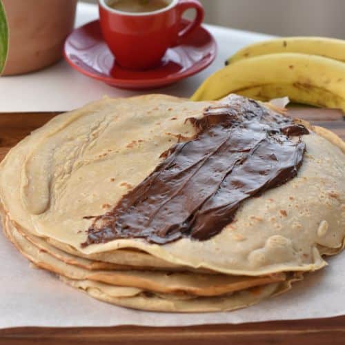 Spreading hazelnut chocolate paste on banana crepes.