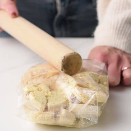 Crushing cookies with a rolling pin.