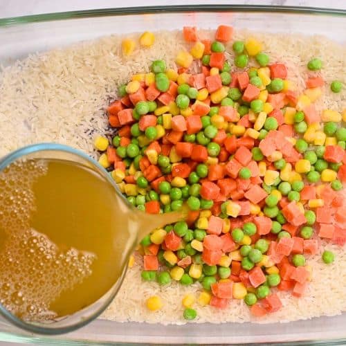 Pouring veggie stock on the rice and veggies.