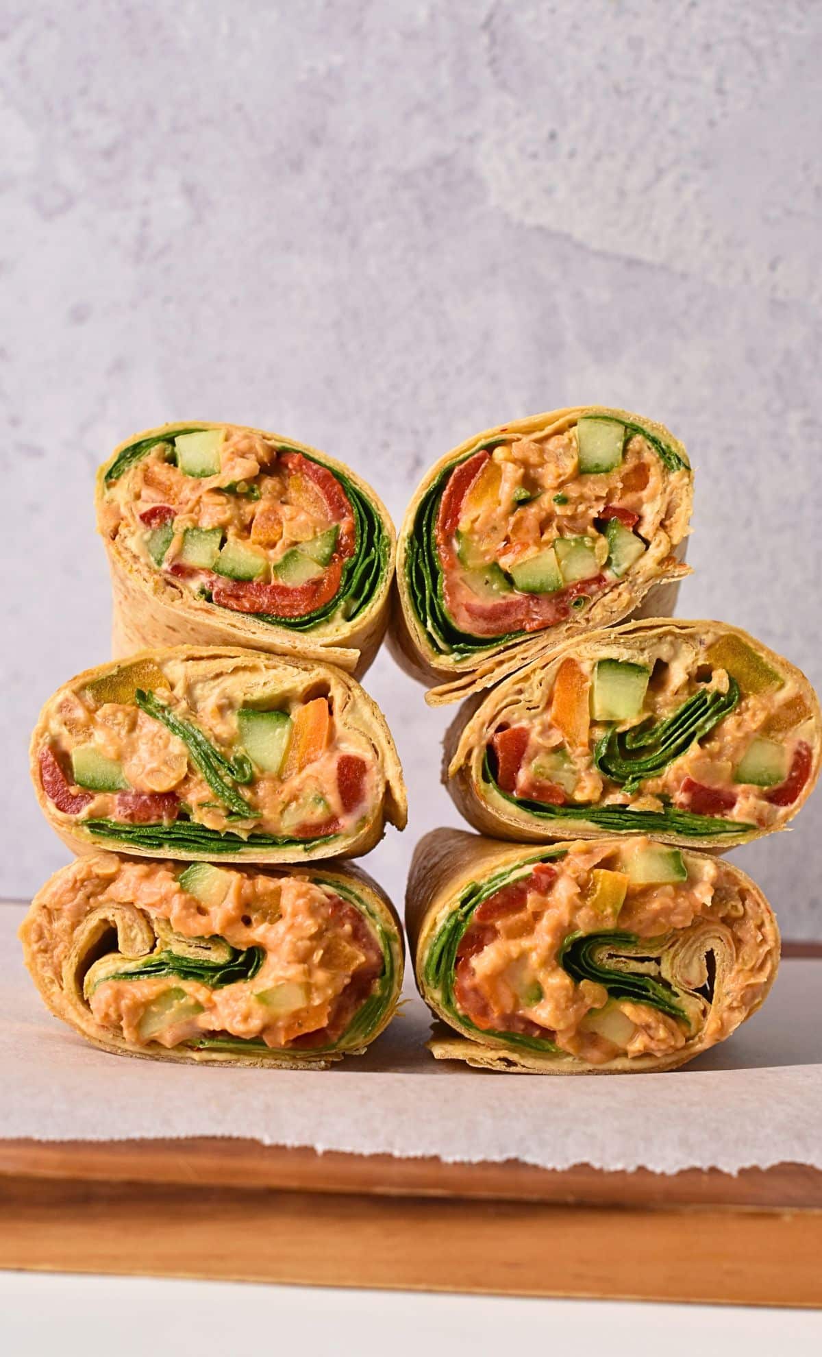 Vegan Hummus Wrap stacked on a wooden plate.