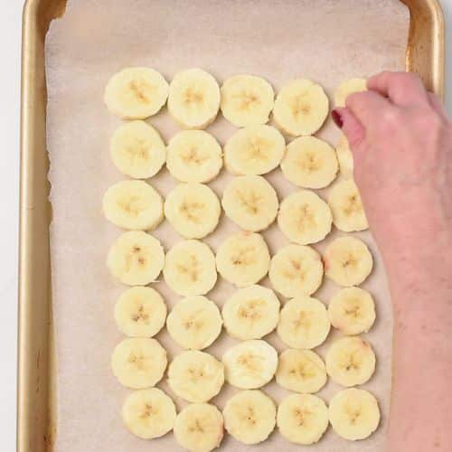 Spreading banana slices on a baking sheet.
