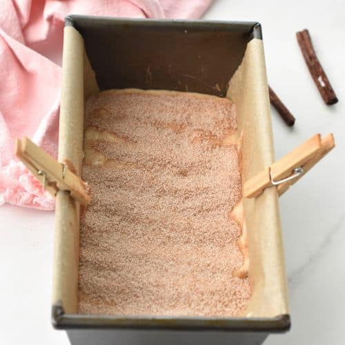 Adding cinnamon sugar to the first layer of Cinnamon Swirl Bread batter.
