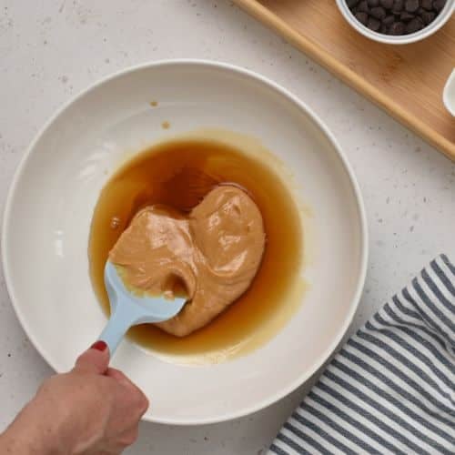 Mixing peanut butter and maple syrup.