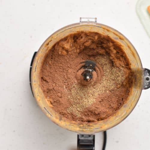 Adding cocoa powder and flaxmeal in the food processor.