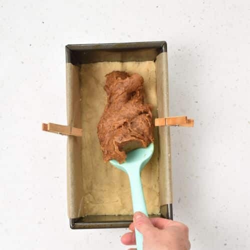 Adding the date caramel to the base in the pan.