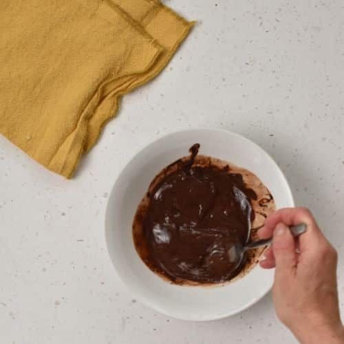 Stirring melted chocolate for the top Healthy Snicker layer.