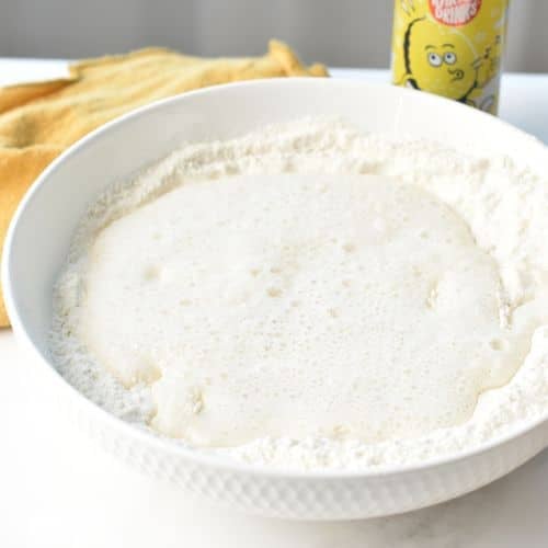 Adding lemonade to the dry Lemonade Cake ingredients in a bowl.