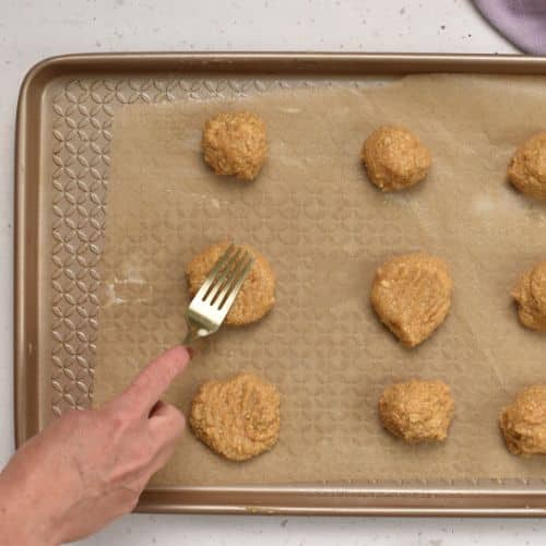 Pressing Cashew Cookies on a baking sheet.