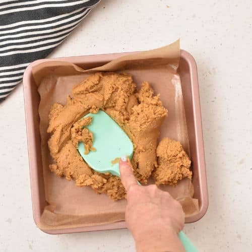 Spreading Peanut Butter Bars in a square pan