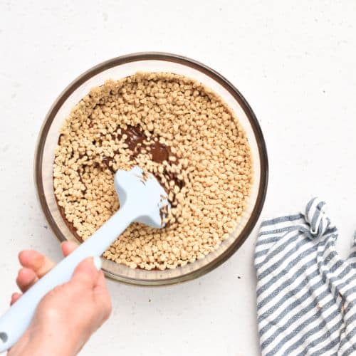 Adding soy crisps to the melted chocolate.