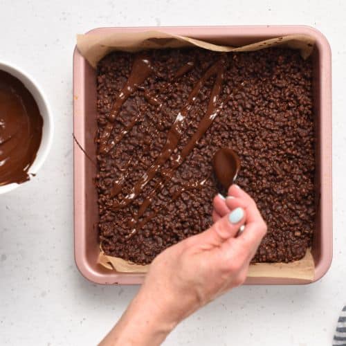 Adding melted chocolate on top of the Protein Crisp Bars.