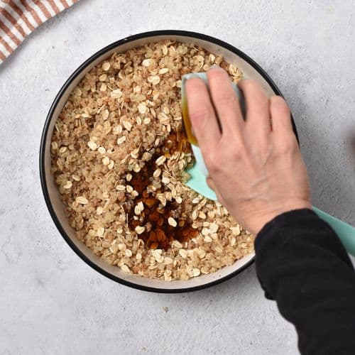 Pouring liquid ingredients on the Quinoa Granola mixture.