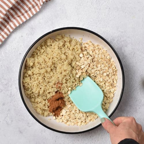 Stirring quinoa and oats in a bowl.