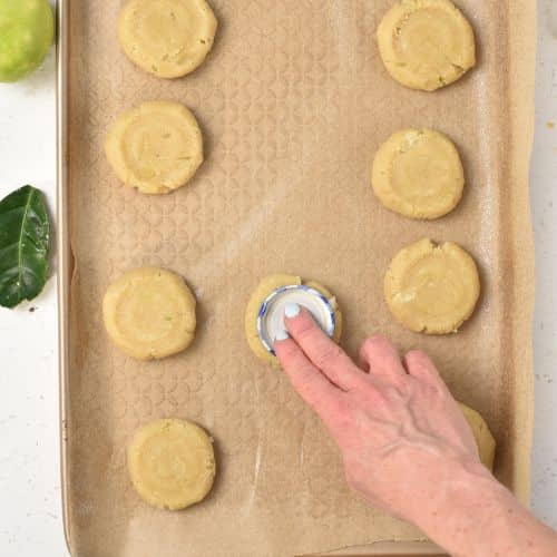 Flattening Key Lime Cookies on a baking sheet.