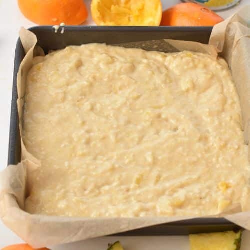 Orange Pineapple Cake in a square pan ready to spread.