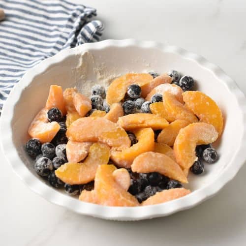 Peach slices and blueberries coated for the Peach Blueberry Cake.