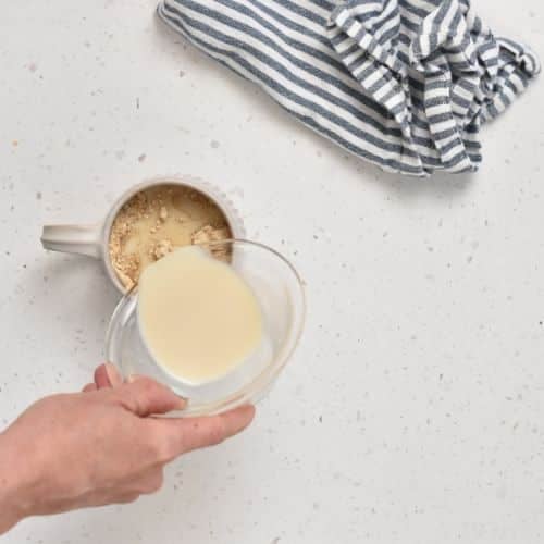 Adding milk to the Peanut Butter Protein Mug Cake dough.