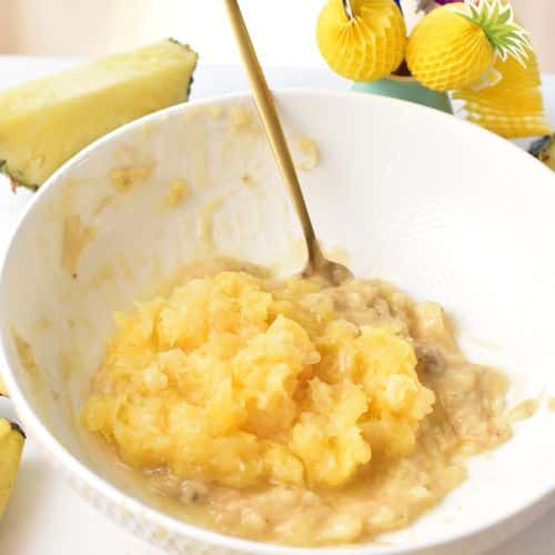Adding crushed pineapple to the mashed bananas.