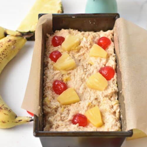 Pineapple Banana Bread dough in the pan with glace cherries on the top.