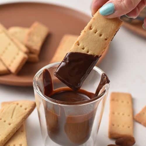 Dipping 3-Ingredient Shortbread Biscuits into melted chocolate.